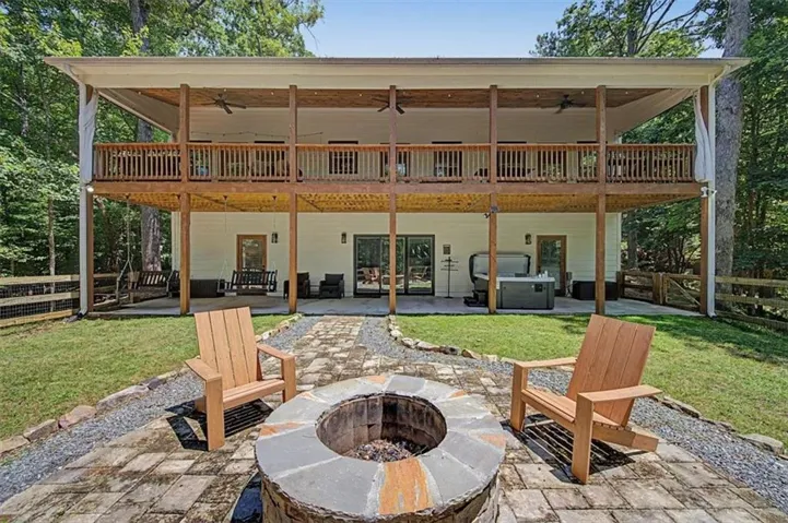 Multi-level deck and covered patio featuring a hot tub and a stone fire pit with paver and gravel pathways