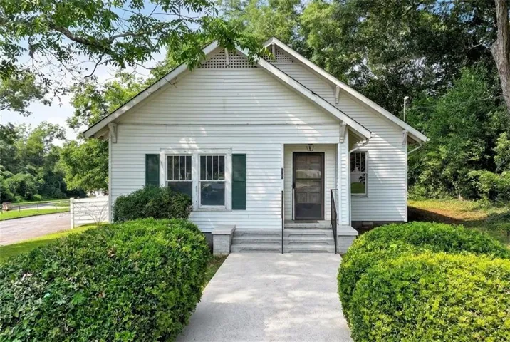 Classic early-1900s bungalow with green shutters and manicured hedges. Enhanced for possibility.
