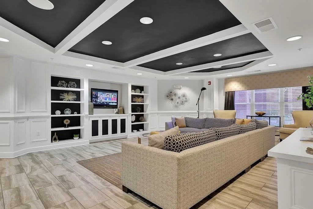 Living area featuring a decorative wall, a raised ceiling, wood tiled floors, and recessed lighting