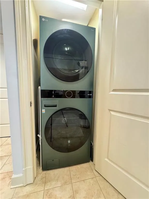 Washroom with stacked washer / drying machine and tile patterned flooring