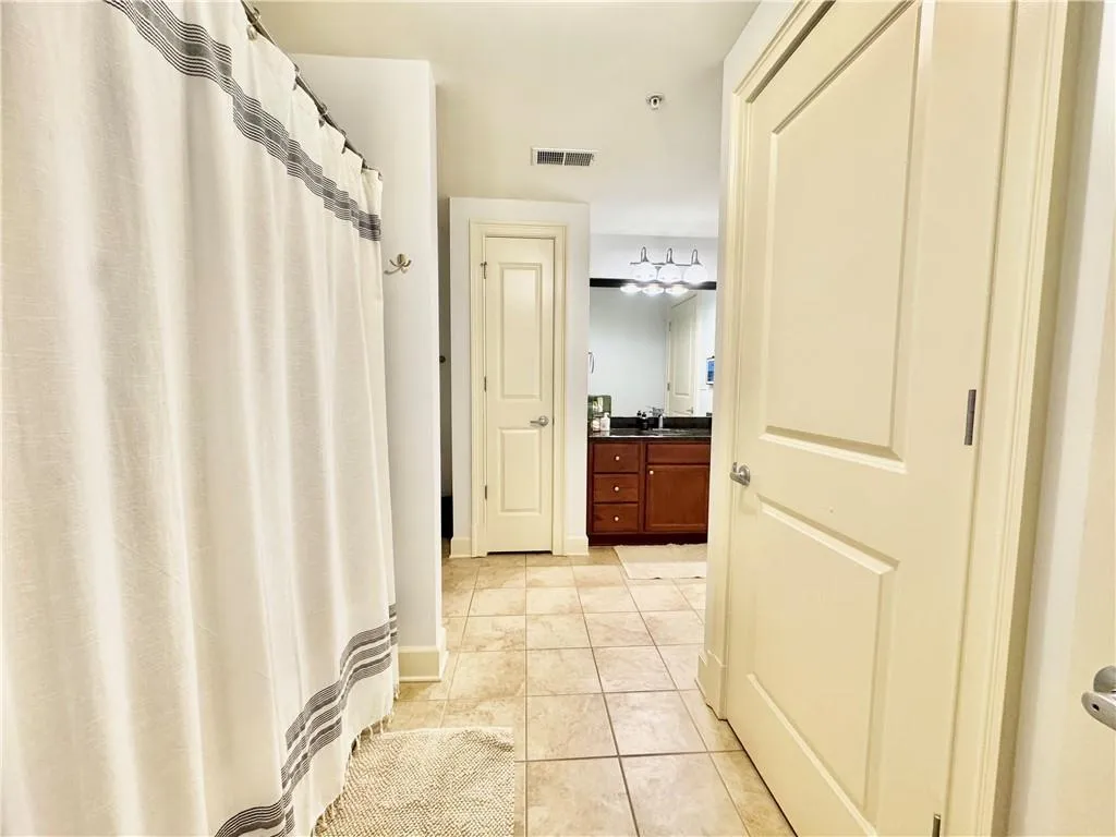 Bathroom with light tile patterned floors, vanity, and curtained shower