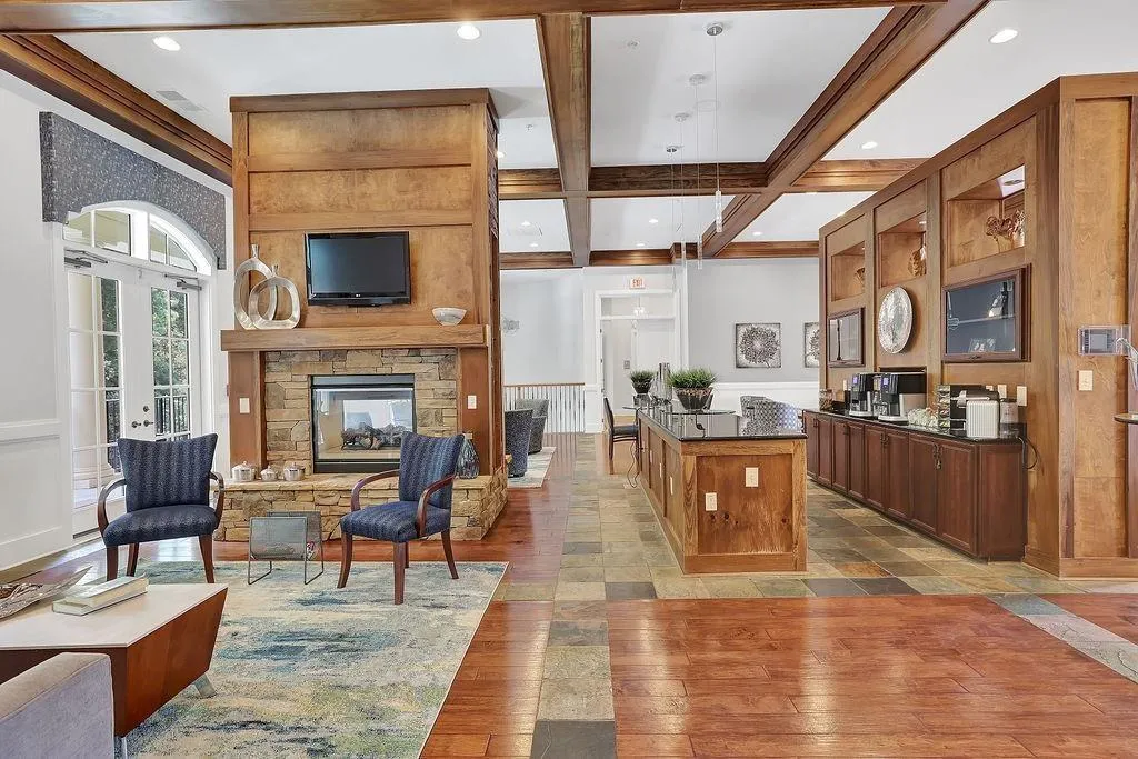 Welcome area featuring beamed ceiling, a stone fireplace, a wainscoted wall, coffered ceiling, and recessed lighting