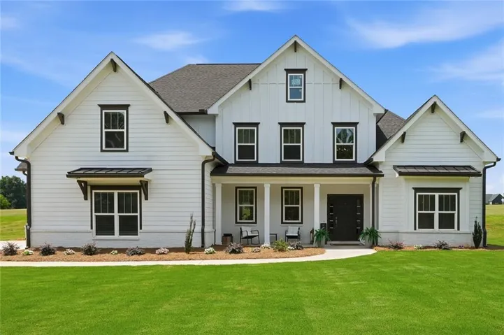 Contemporary farmhouse exterior with board and batten and horizontal siding, featuring a covered porch, dark trim accents, and a professionally landscaped yard