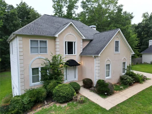 Two-story residence featuring a neutral stucco exterior with decorative trim and white siding accents