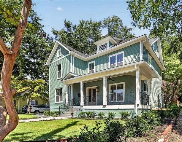 Two-story residence with a covered front porch featuring white columns and a black wrought-iron railing