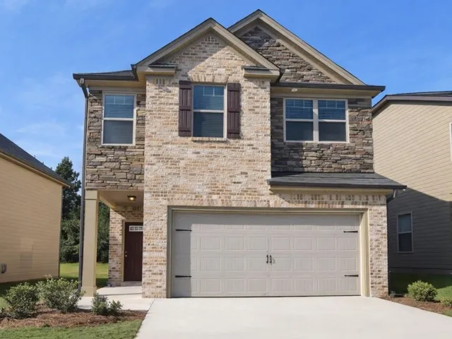 Two-story residence featuring a brick and stone facade, an attached two-car garage, and a covered entryway