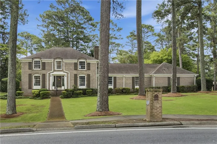 Traditional brick exterior with a symmetrical facade, dormer windows, and dark shutters