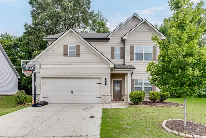 Charming two-story home featuring a light-colored siding exterior, pitched roofline with architectural detail, and a spacious driveway