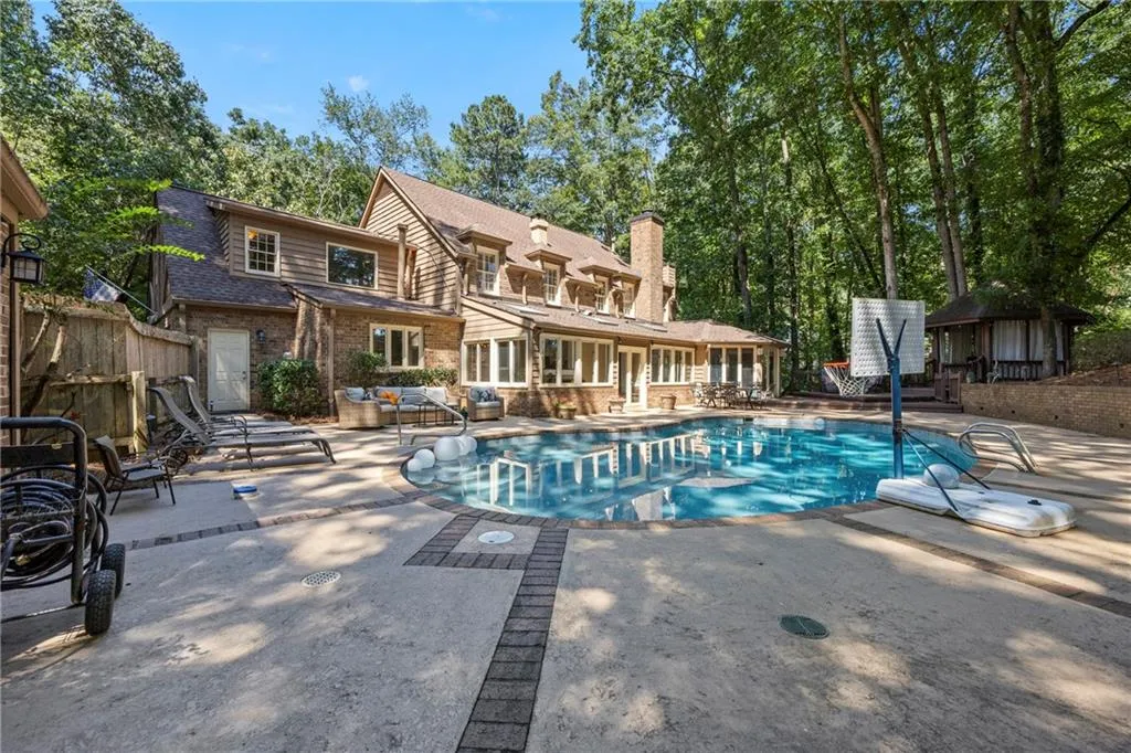 Swimming pool with a patio and view of wooded area