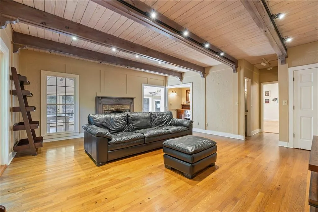 Living room with a wood ceiling with exposed beams, light wood-type flooring, a fireplace, and rail lighting