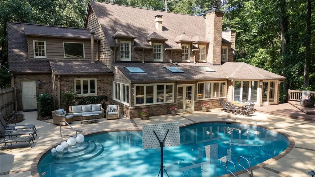 Back of property with a sunroom, a patio, outdoor lounge area, brick siding, and an outdoor pool