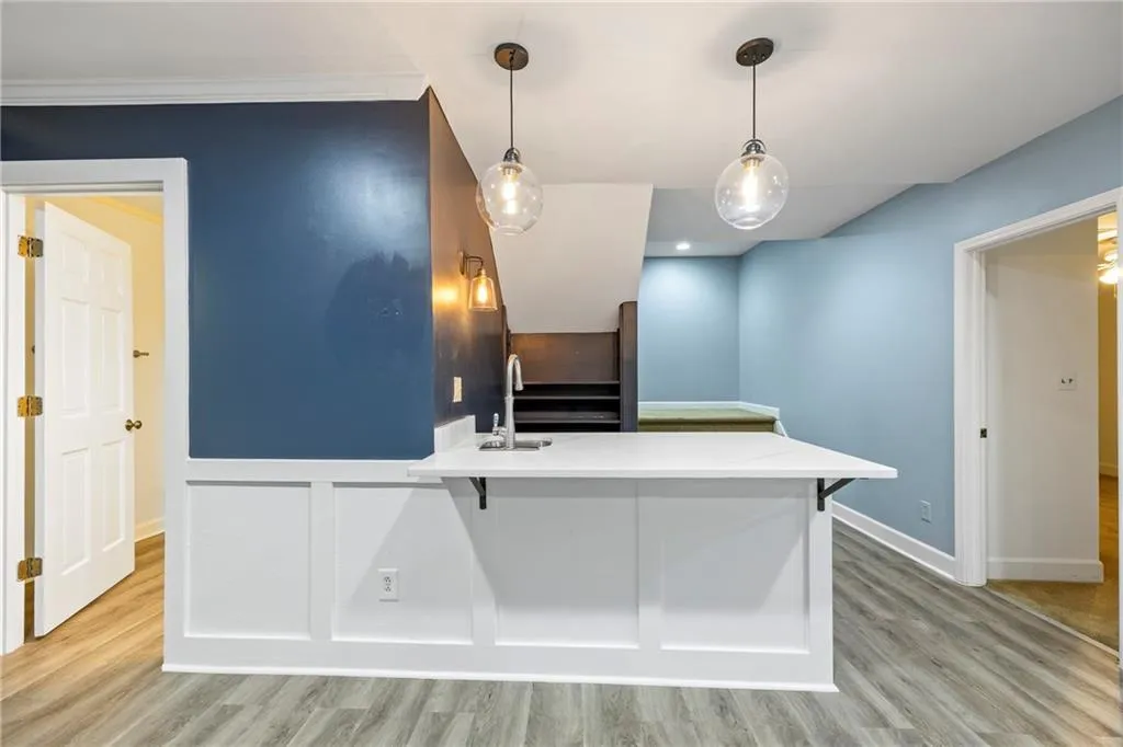 Kitchen with a breakfast bar, light wood-type flooring, decorative light fixtures, and a peninsula