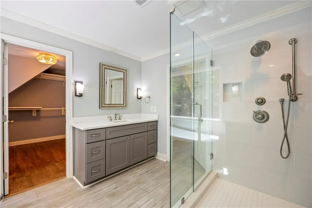 Full bathroom with a stall shower, vanity, crown molding, light wood-type flooring, and a walk in closet