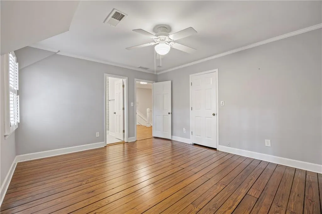 Unfurnished bedroom with ornamental molding, hardwood / wood-style flooring, and ceiling fan