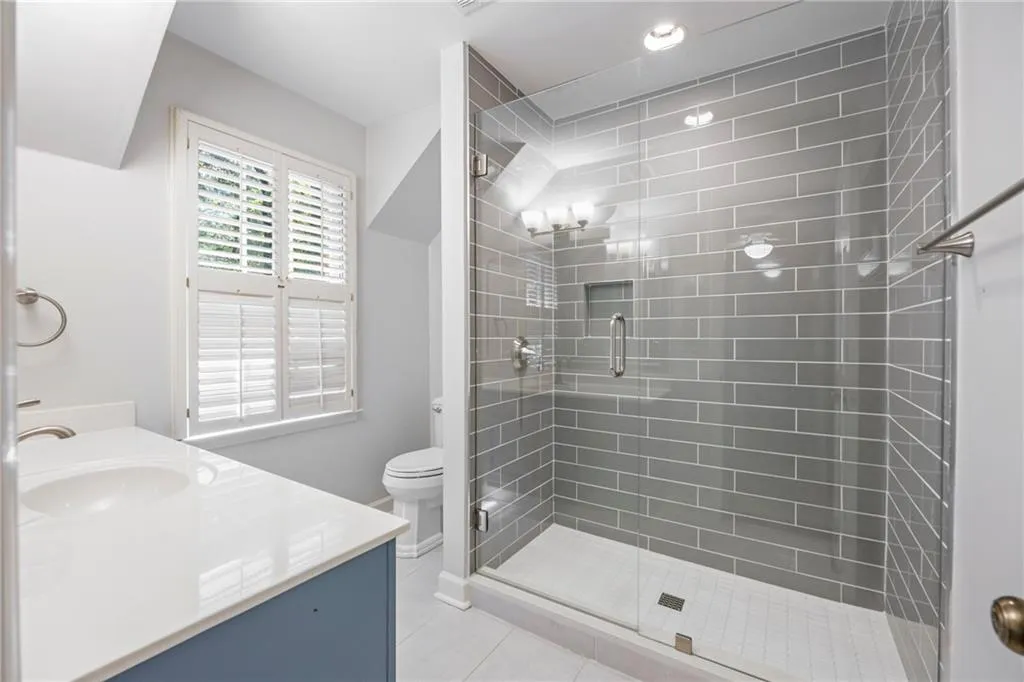 Full bath featuring vanity, a stall shower, light tile patterned flooring, and recessed lighting