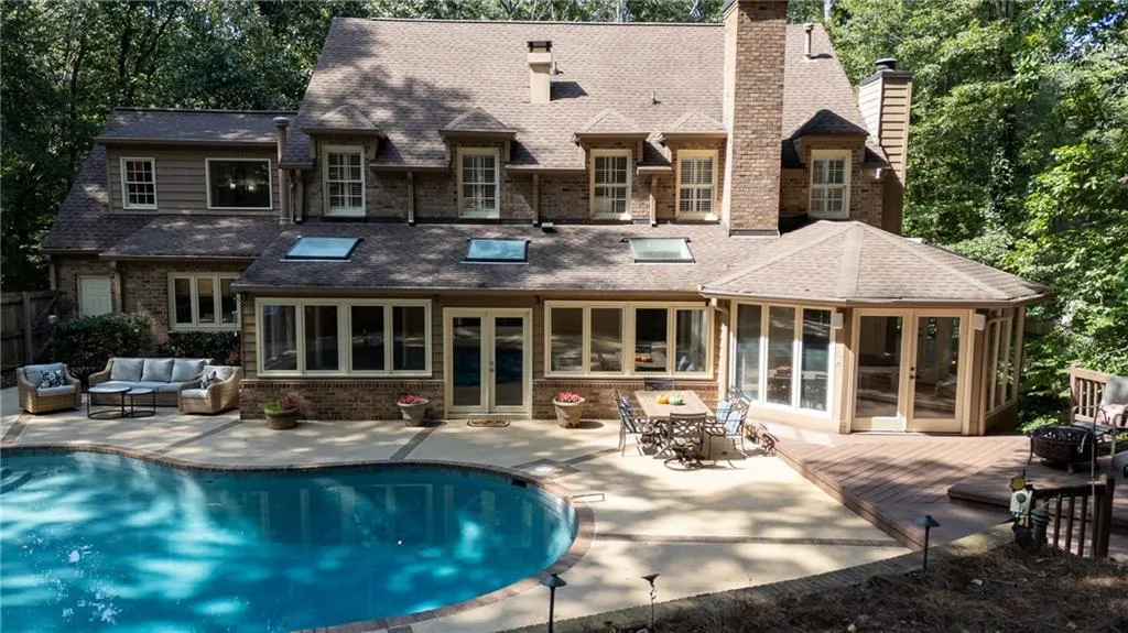 Back of house featuring a sunroom, outdoor lounge area, a patio area, french doors, and a chimney