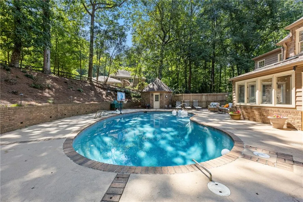 View of pool with a fenced backyard, view of wooded area, a patio, an outbuilding, and a sunroom