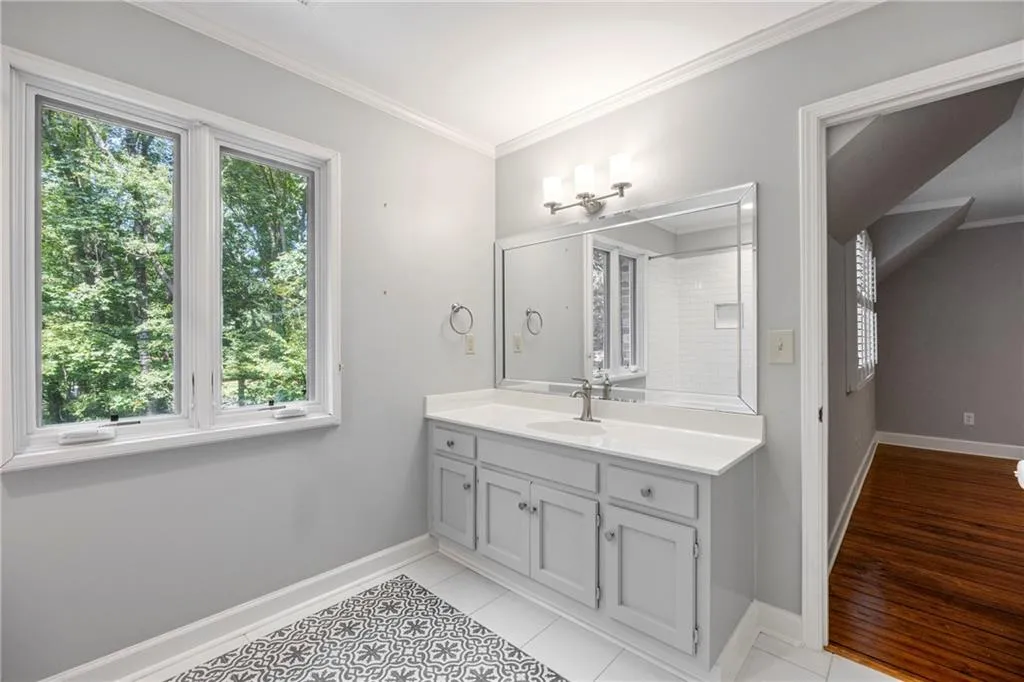 Full bath featuring ornamental molding, vanity, and light tile patterned floors