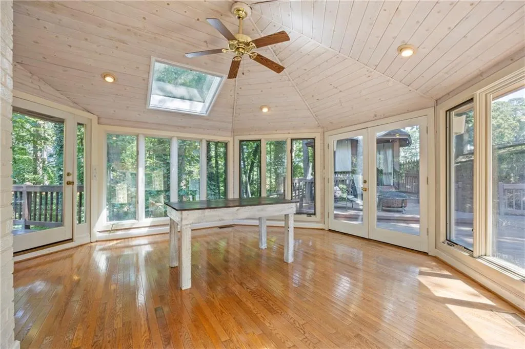 Unfurnished sunroom with recessed lighting, wood-type flooring, a skylight, vaulted ceiling, and plenty of natural light