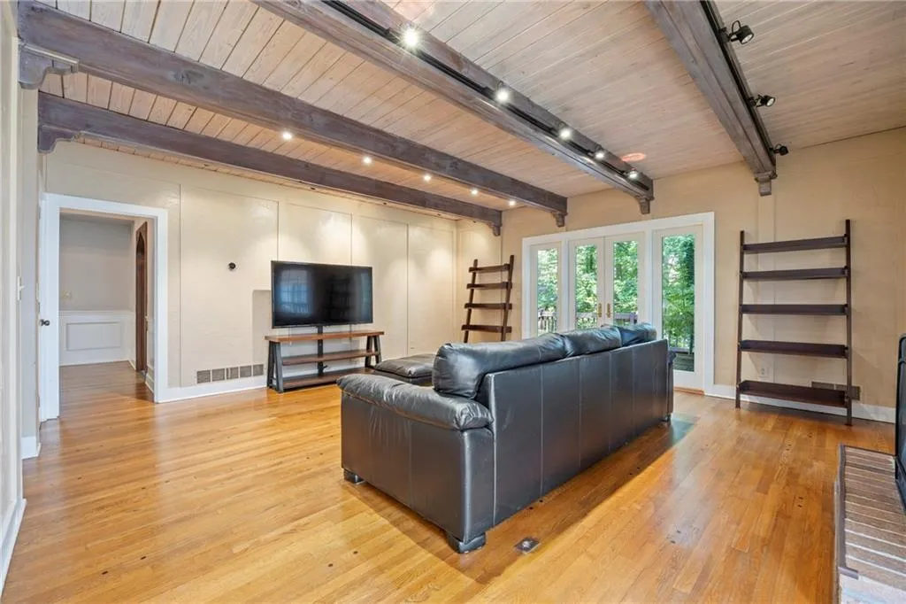 Living room with light wood-type flooring, a wooden ceiling with exposed beams, and french doors