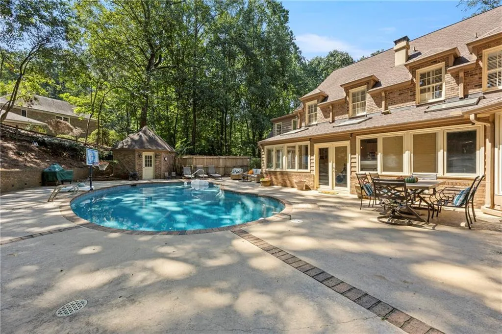 View of pool featuring a sunroom, an outbuilding, a patio, outdoor dining space, and view of scattered trees