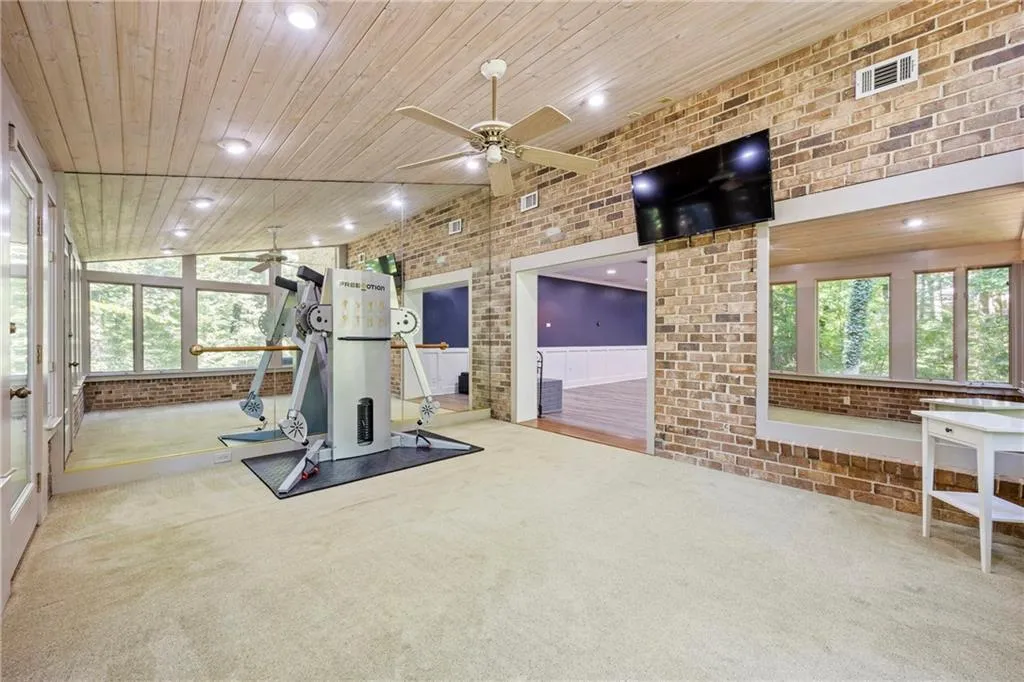 Exercise room featuring brick wall, healthy amount of natural light, recessed lighting, a ceiling fan, and carpet floors
