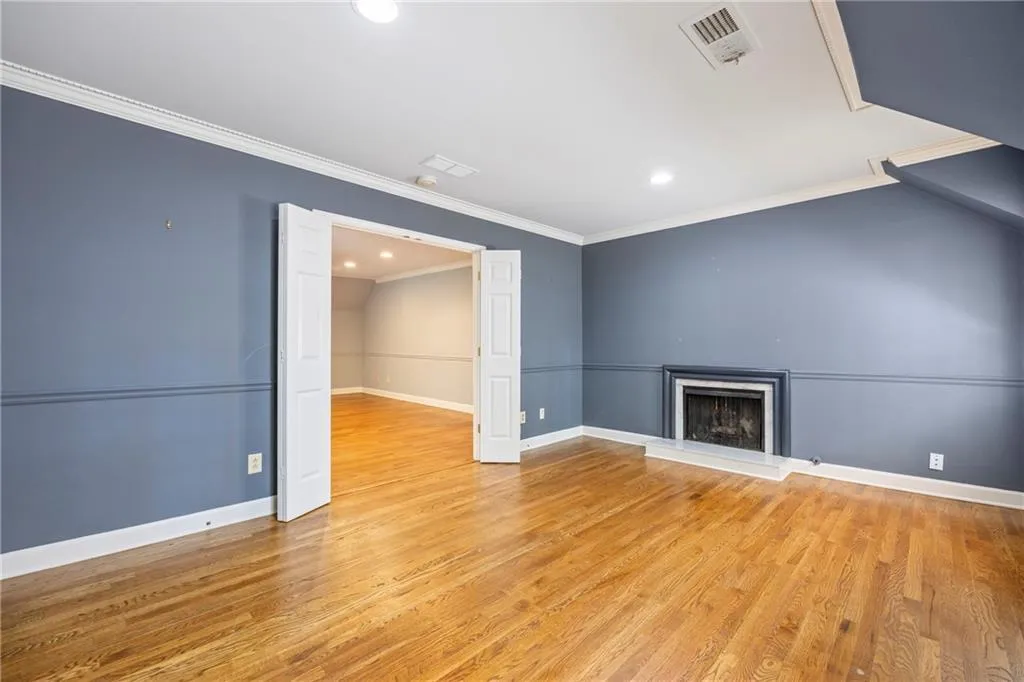 Unfurnished living room with crown molding, light wood-style floors, a fireplace with raised hearth, and recessed lighting
