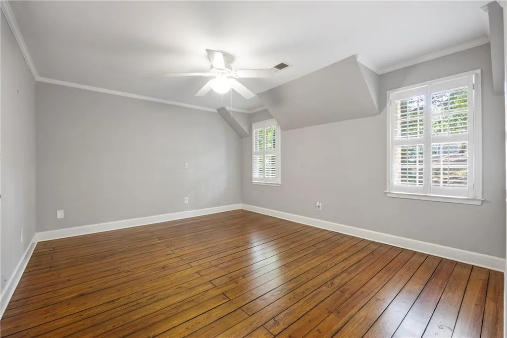 Additional living space with healthy amount of natural light, dark wood finished floors, and a ceiling fan