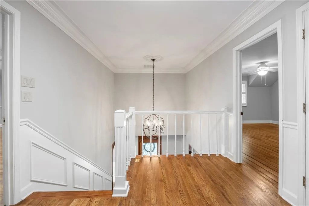 Hallway featuring an upstairs landing, ornamental molding, a chandelier, and wood finished floors