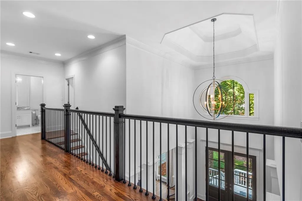 The corridor includes crown molding, hardwood flooring, a chandelier, an upstairs landing overlooking the front entryway The corridor includes crown molding, hardwood flooring, a chandelier, an upstairs landing overlooking the front entryway