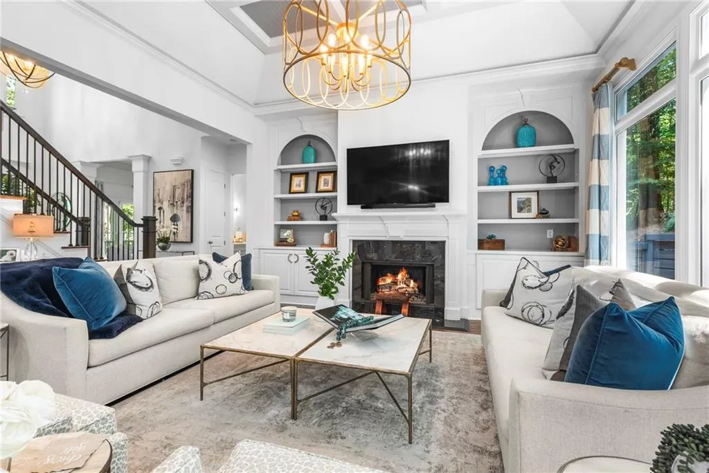 Family room featuring plenty of natural light with a wall of windows, coffered ceiling, fireplace, built-ins and designer chandelier Family room featuring plenty of natural light with a wall of windows, coffered ceiling, fireplace, built-ins and designer chandelier