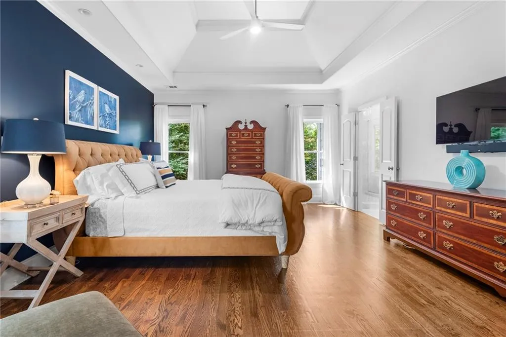 Primary Bedroom featuring sitting area,10’ ceiling with tray, ornamental molding, recessed lighting, ceiling fan and hardwood floors Primary Bedroom featuring sitting area,10’ ceiling with tray, ornamental molding, recessed lighting, ceiling fan and hardwood floors