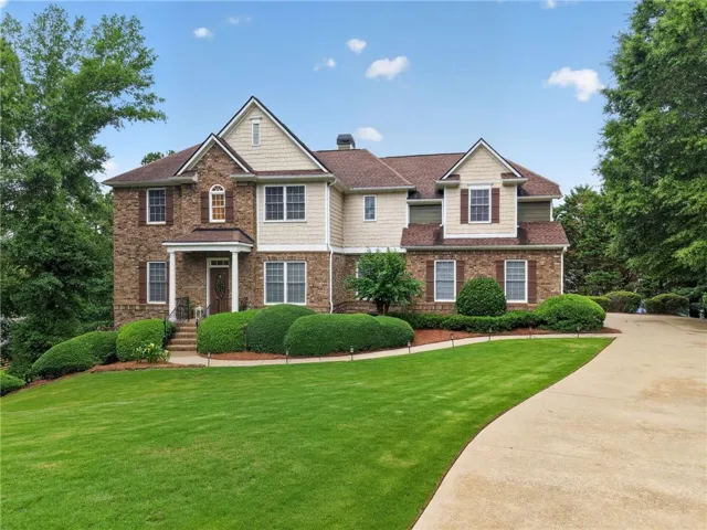 Two-story brick and siding residence featuring a gabled roofline, front portico, and contrasting window shutters