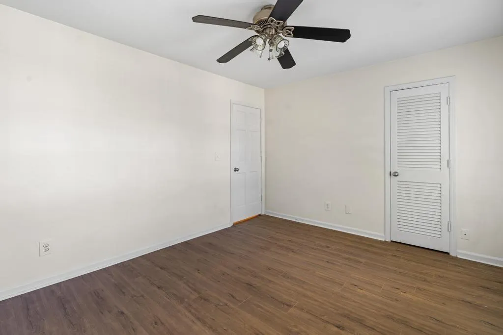 Unfurnished bedroom featuring dark wood-type flooring and ceiling fan