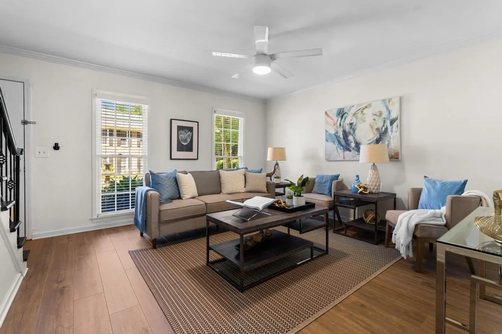 Living room featuring wood finished floors, crown molding, stairs, and a ceiling fan