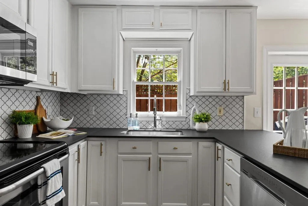 Kitchen with appliances with stainless steel finishes, tasteful backsplash, and white cabinets