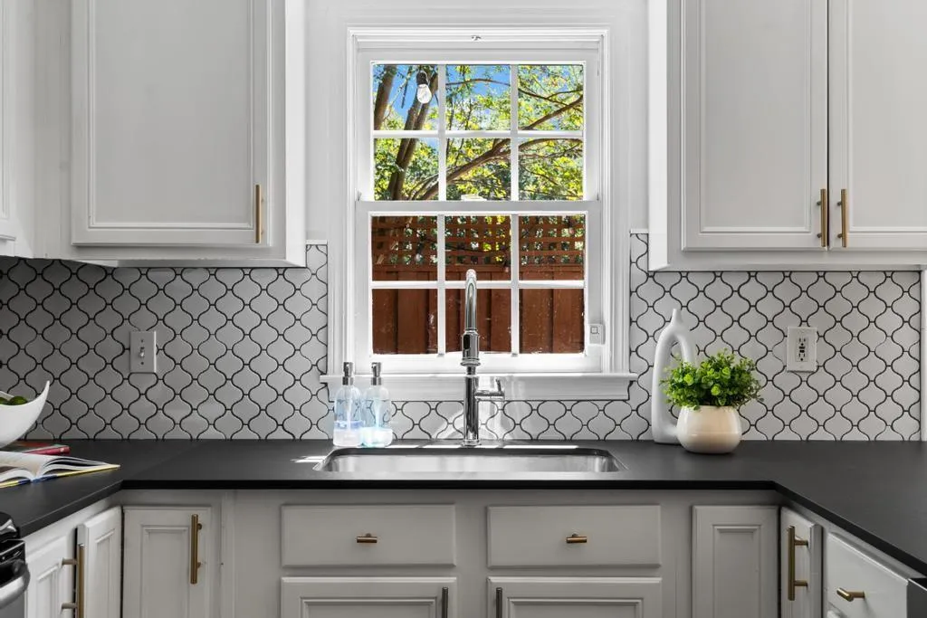 Kitchen with tasteful backsplash and white cabinetry