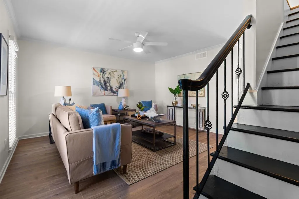 Living area with stairs, dark wood-style flooring, ornamental molding, and a ceiling fan