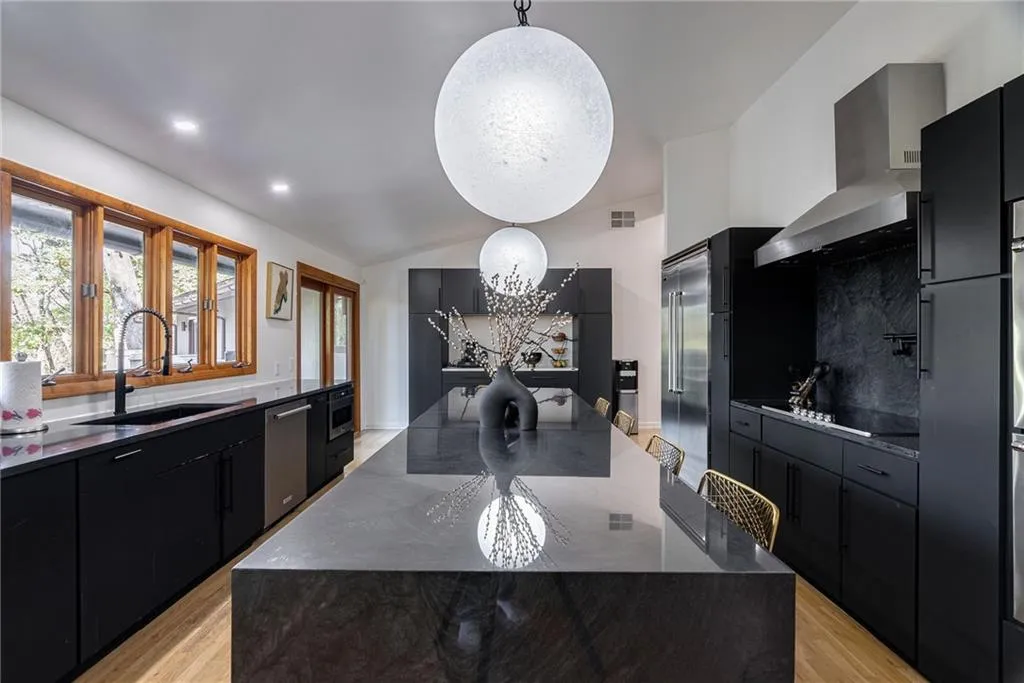 Kitchen featuring pendant lighting, dishwasher, a spacious island, sink, and wall chimney exhaust hood