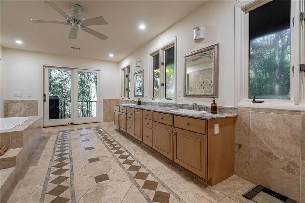 Bathroom with a relaxing tiled tub, vanity, and ceiling fan