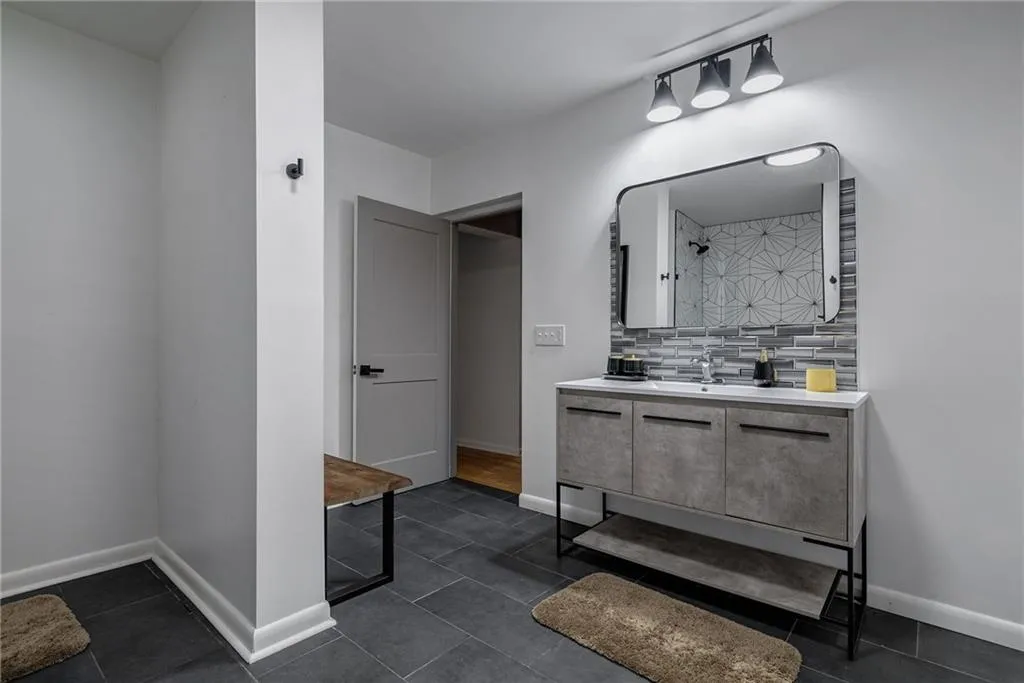 Bathroom featuring tile patterned flooring, vanity, and tasteful backsplash