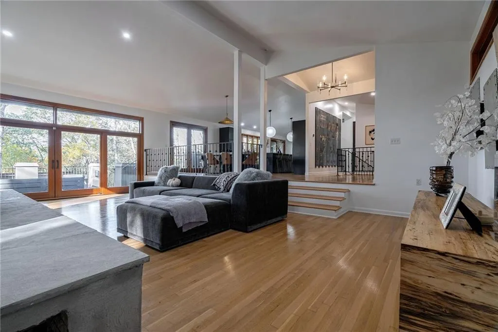 Living room with wood-type flooring, lofted ceiling, and an inviting chandelier