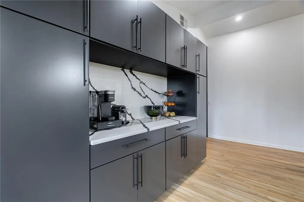 Kitchen featuring gray cabinets, light hardwood / wood-style floors, light stone counters, and built in fridge
