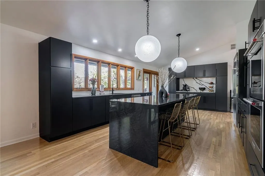Kitchen with sink, pendant lighting, light hardwood / wood-style flooring, a center island, and lofted ceiling