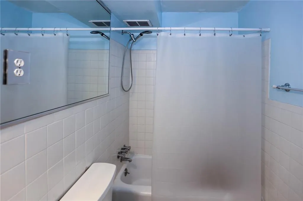 Full bathroom with shower/bath combo with shower curtain and tile walls