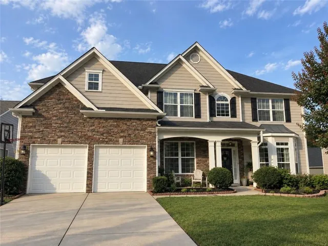 Stone and siding exterior with a covered entry, column accents, bay window, and two-car garage