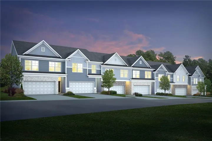 Townhome community featuring gabled rooflines, stone veneer accents, individual attached garages, and a paved street