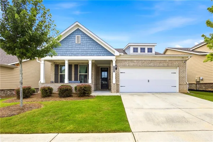 Light brick exterior featuring blue decorative shingles and a covered front porch