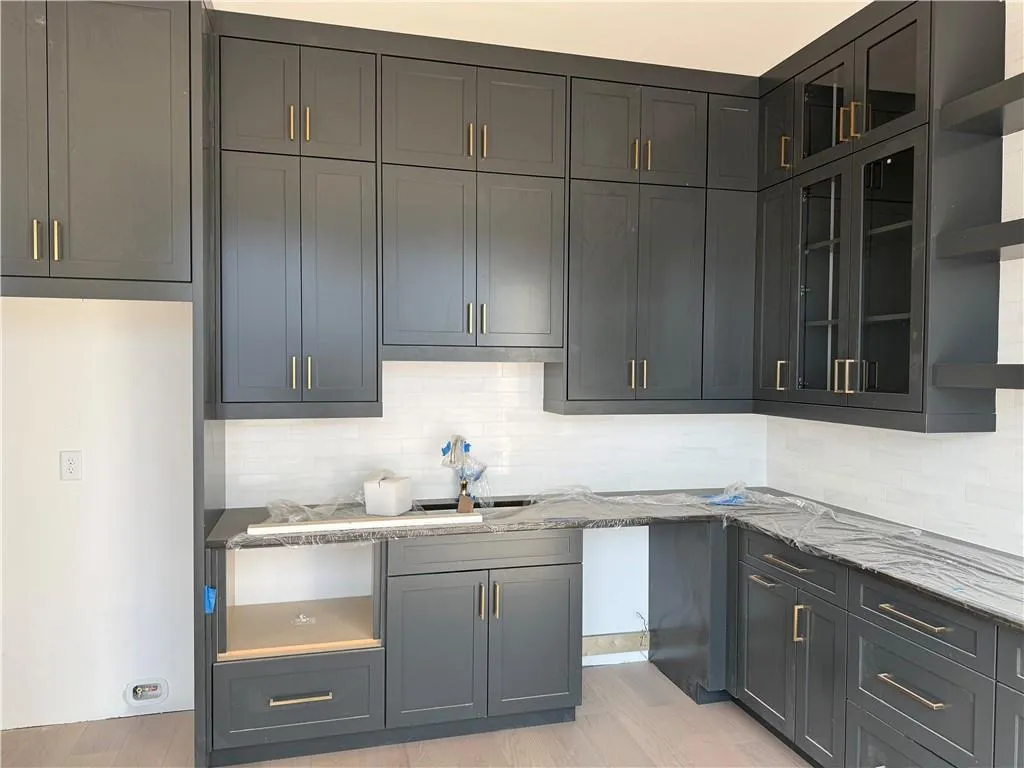 Kitchen with glass fronted cabinets, light stone countertops, open shelves, and decorative backsplash