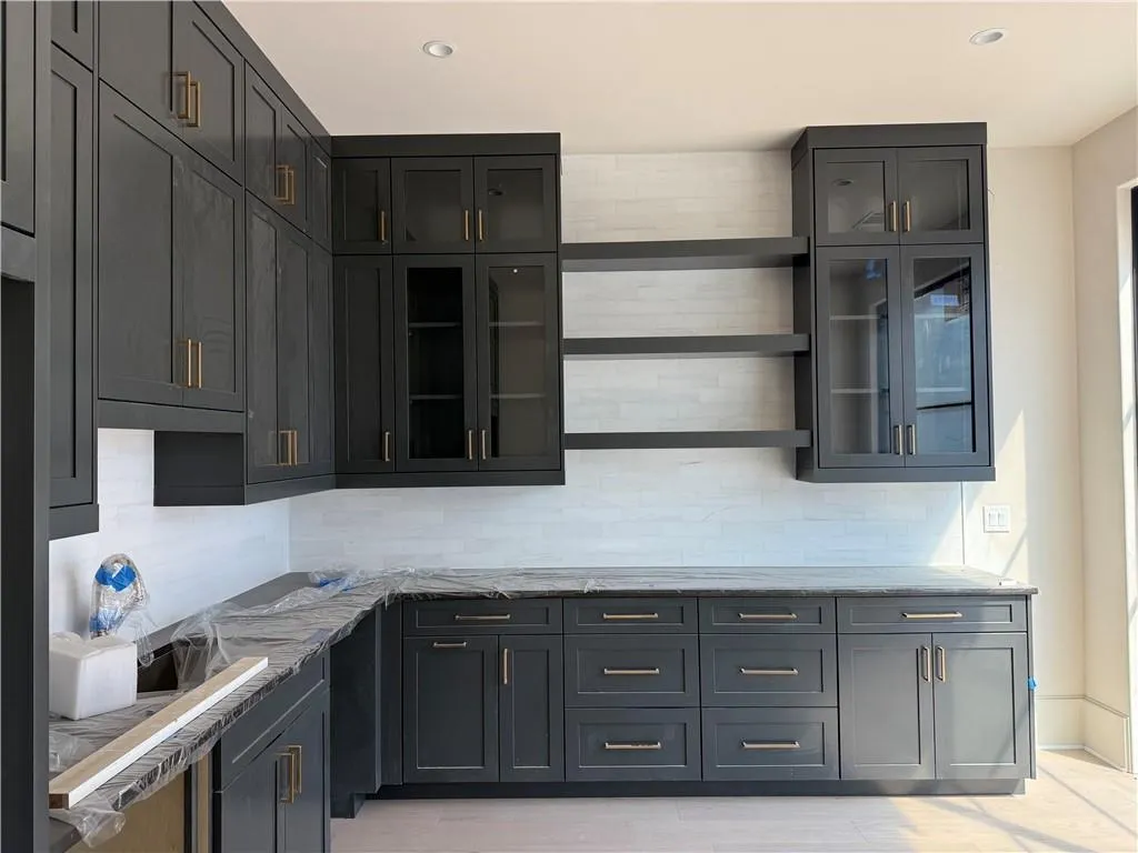 Kitchen with open shelves, light stone countertops, glass fronted cabinets, decorative backsplash, and recessed lighting